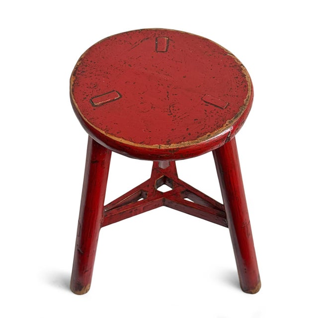 Vintage red painted wooden stool. Round seat with three legs. Aged finish adds character and charm.