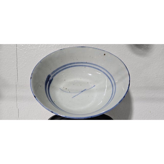 A unique ceramic bowl featuring blue floral motifs; the maker's name is hand-painted on the underside. This is a...