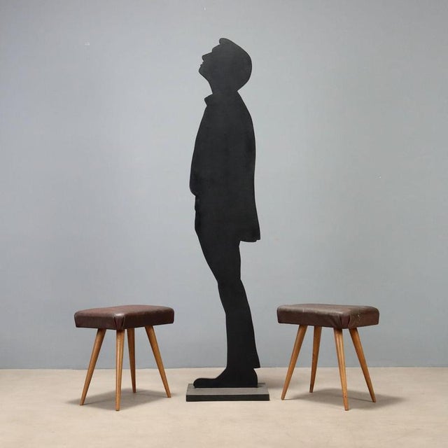 Pair of vintage 1950s stools featuring tapered beech wood legs with seats upholstered in brown faux leather, a material...