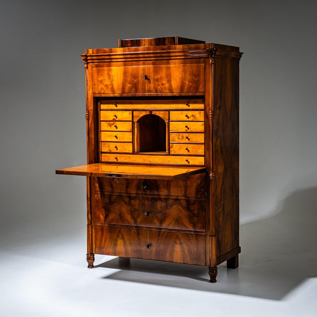 Biedermeier secretary desk veneered in walnut, featuring three lower drawers, a flat fall-front writing surface, and a top...