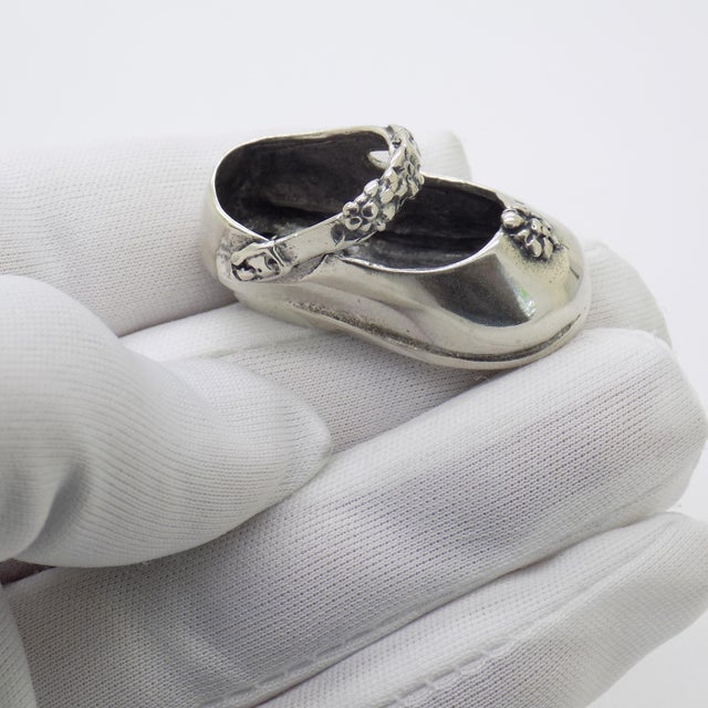 A charming vintage miniature depicting a baby shoe with floral decoration, handmade in Continental Silver (800/000) in...