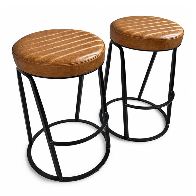 A sophisticated counter stool upholstered in warm nubuck leather featuring a classic tufted seat and back that bring...