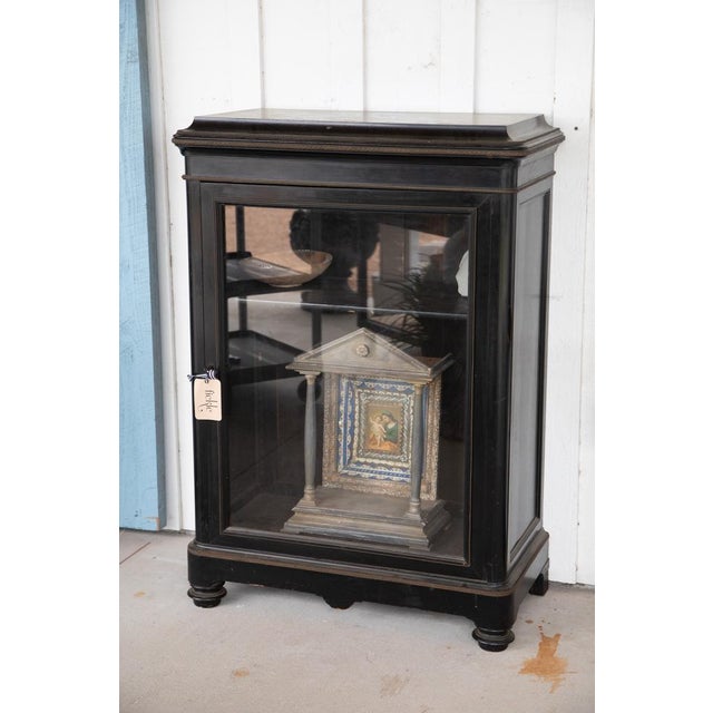 French cabinet from the 1870’s with a revealing glass paneled door. Brass metalwork lining the edges of the piece bring a...