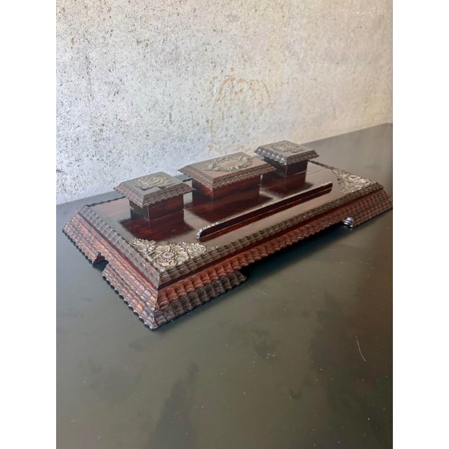 An elegant antique rosewood desk stand featuring three lidded inkwells, silver-mounted decorative accents, and richly...
