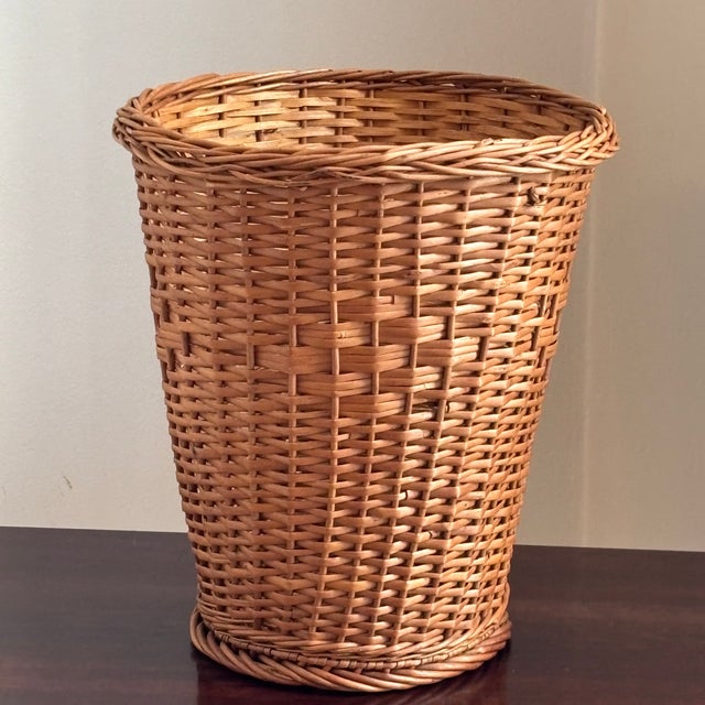 Offering a lovely handwoven natural wicker wastebasket from the mid-20th century. In addition to being highly functional,...