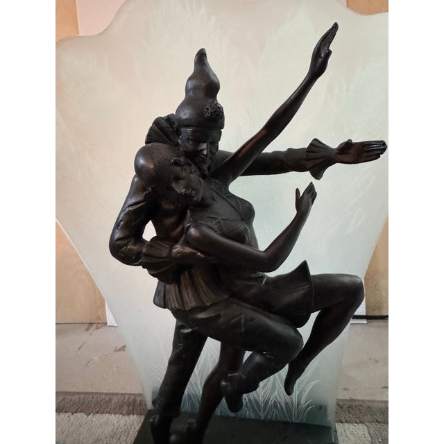 Striking vintage illuminated table sculpture featuring a dramatic Harlequin and ballerina posed in front of a large...