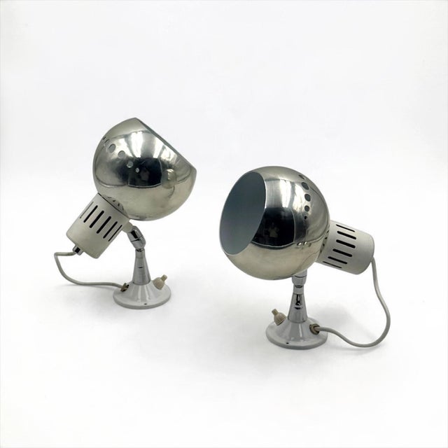 A matching pair of unused Space Age wall lamps from the 1970s, characterized by polished chrome-finished metal shades and...