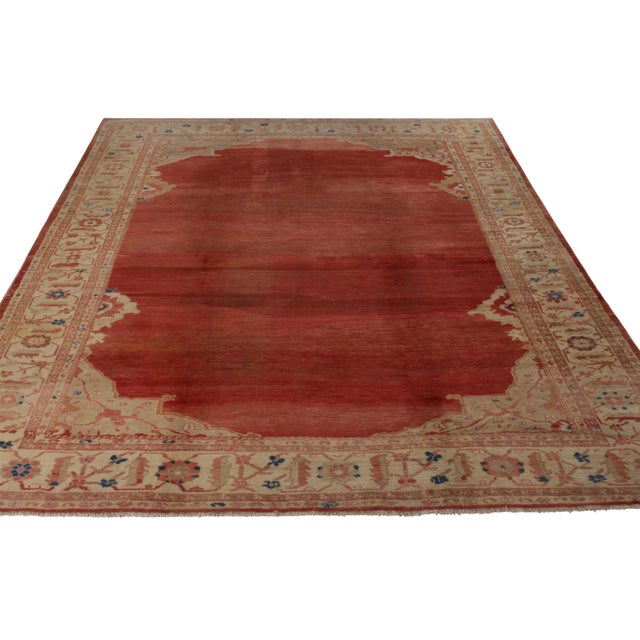 A 10x13 antique Persian rug of Sultanabad origin and rare open-field design in red and beige-brown. Hand-knotted in wool...