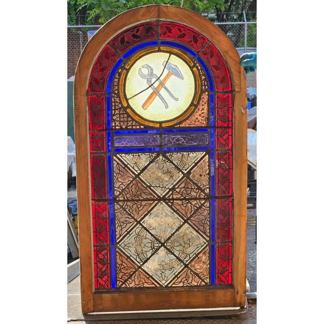 C. 1873 Romanesque Revival style leaded, stained glass church window having painted upper roundel featuring the "hammer...