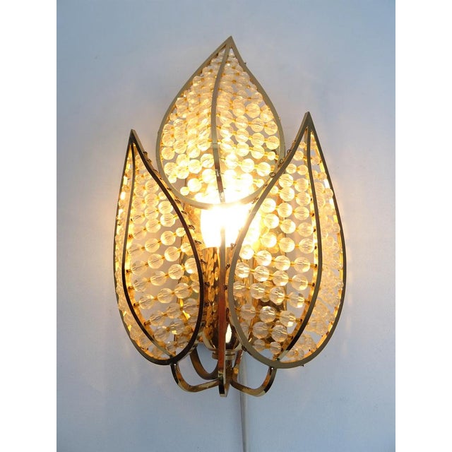Lovely and extraordinary wall sconce with a brass frame and crystal glass. The lamp has an incomparable unique character....