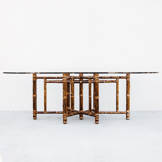Monumental bamboo and laced rawhide pedestal base dining table by McGuire from the 1980s. The beveled glass top measures...