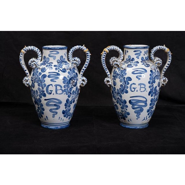 A pair of Neapolitan glazed majolica vases depicting pastoral scenes, dating from the late 19th century. The body is ovoid...