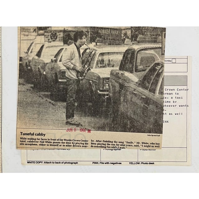 1982 black and white photograph of a cab driver playing the saxophone as he waits for fares outside the Westin in Kansas...