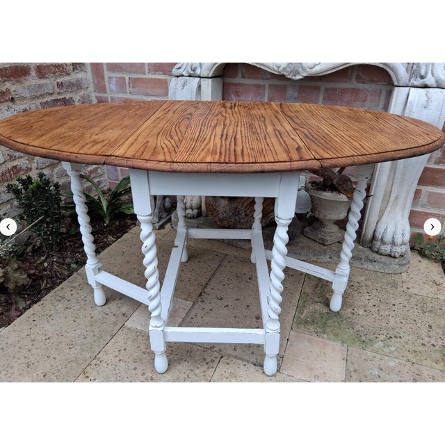 An antique folding table, made of oak with Barley Twist legs, now shines in shabby white with a sanded, oiled top. This...