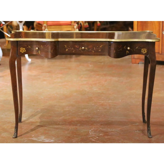 Graceful curves and colorful floral marquetry give this Mid-Century Louis XV style writing desk an elegant decorative...