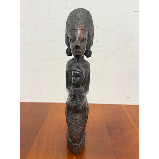 Design Plus Gallery presents an African Wood Carved Mother + Child Figure. This hand carved sculpture shows a standing...