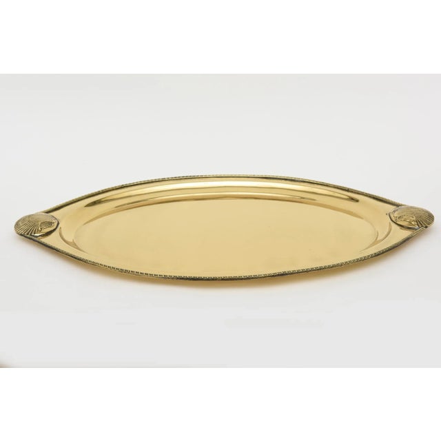 This lovely vintage brass oval tray has 2 shell designs at either end. There is a braided perimeter brass design surround....