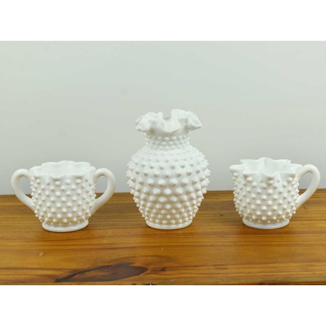 Elevate your home decor or coffee service with this classic three-piece collection of vintage Fenton milk glass in the...