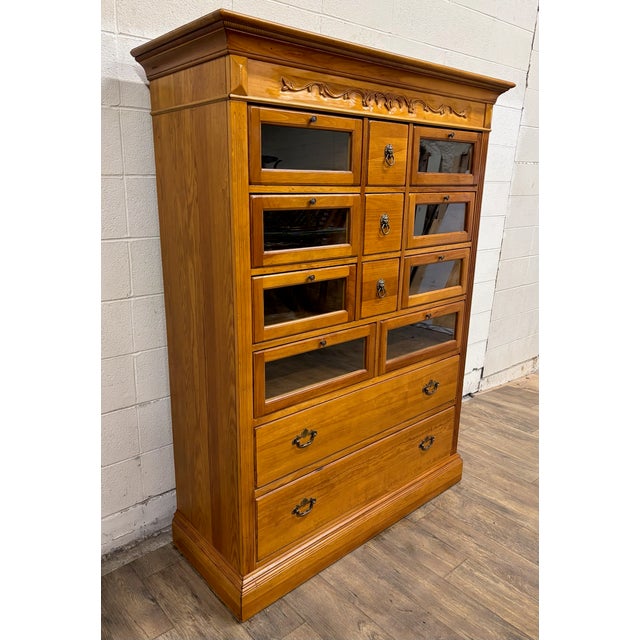 This is a stunning and rare vintage wood Haberdashery, Haberdasher, or apothecary cabinet with glass fronted drawers and...