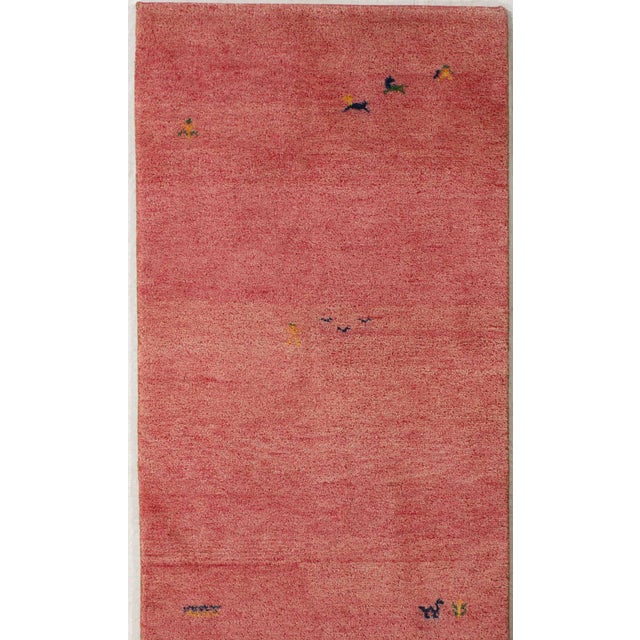 Hand-knotted Gabbeh wool rug featuring a soft red field with scattered small stylized animal and plant motifs. Indo Gabbeh...