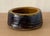 A small vintage studio pottery ring dish or pinch bowl with a low cylindrical form and richly layered earth-tone glaze....