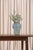 A frosted pale aqua vase in an amphora-like shape, with a flared lip and a body that tapers toward the base. Two hand-...