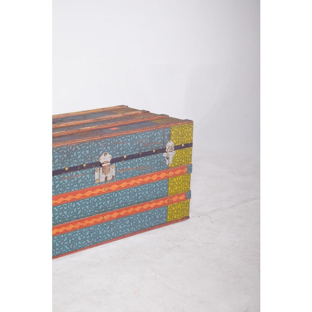 Wooden trunk in shades of green, blue, and orange. with a sturdy structure and decorated with vibrant graphic patterns,...
