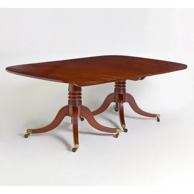 This exquisite antique English George III-style mahogany dining table exudes sophistication and classic refinement, a...