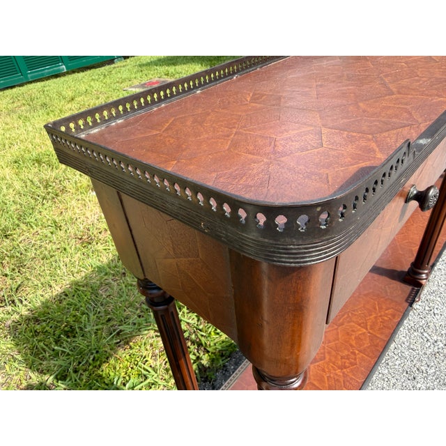 A leather panelled and solid wood console table, decorated throughout with verdigris brass mounts, the galleried top above...