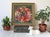 Framed vintage needlepoint wall hanging featuring a festive fruit and angel wreath. Professionally frame. Some age wear to...