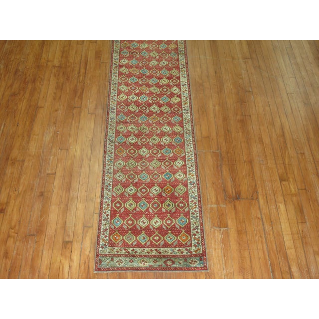 A late 19th Century narrow turkish runner on a red field. Professionally Cleaned and able to endure heavy traffic if...