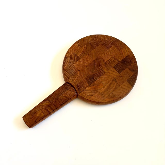 A mid century teak cutting board designed by Jens Quistgaard for Dansk, made in Thailand. Circular shape with a knife that...