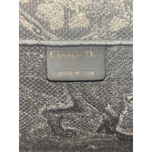 The Dior Book Tote has become a quintessential staple of luxury streetwear and travel elegance. This specific medium-sized...