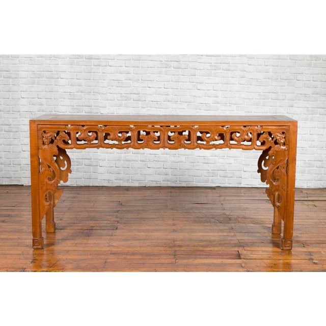A Chinese altar console table from the early 20th century, with cloudy carved apron and scrolling feet. Created in China...