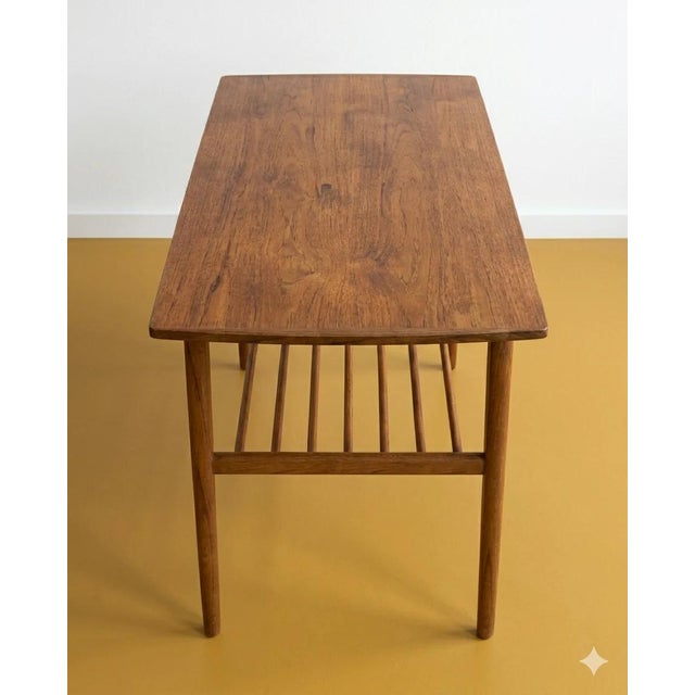 Danish coffee table from the 1950s in teak, featuring a rectangular top with rounded corners and a slatted lower shelf—a...