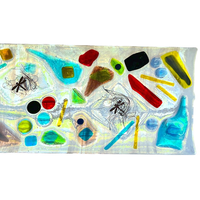 Playful and sculptural fused art glass tray featuring an abstract composition of jewel-toned geometric forms suspended...