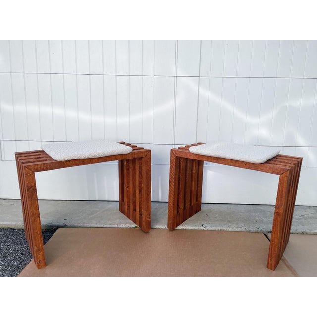 A pair of Scandinavian Modern benches or ottomans, hand-crafted from slatted pine wood with a warm brown finish. The open-...