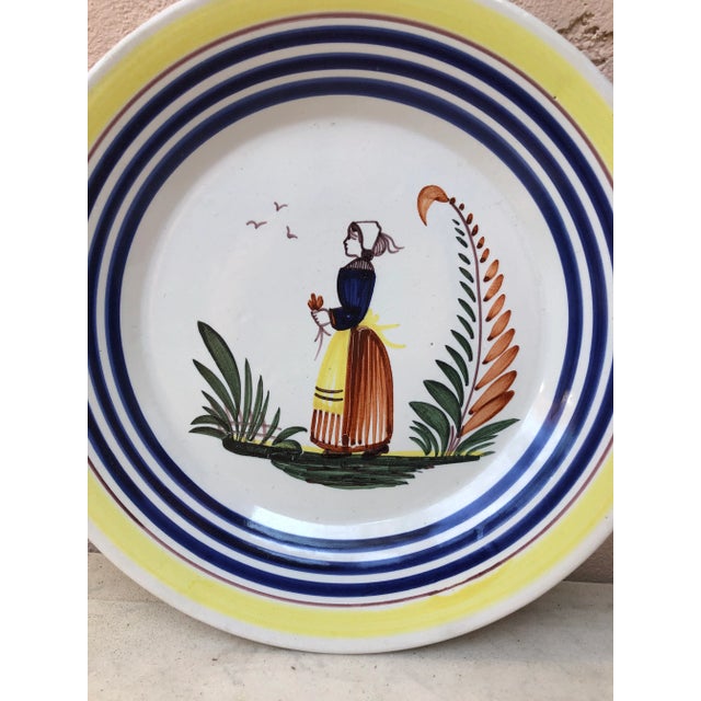 A French large faience plate with a farmer in the costume with flowers signed Henriot Quimper, circa 1950. Colorful yellow...