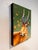 This artwork features a striking antelope adorned with vibrant purple horns, set against a rich green background. Delicate...