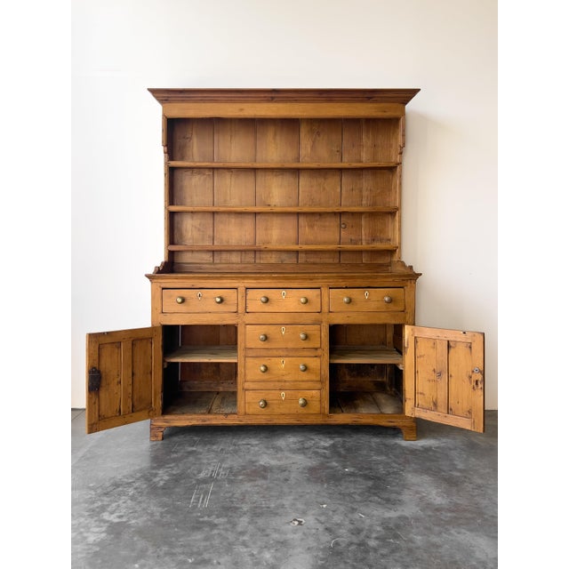 A striking antique English pine kitchen dresser/hutch with ample beautiful character. Comes apart in two pieces for easy...