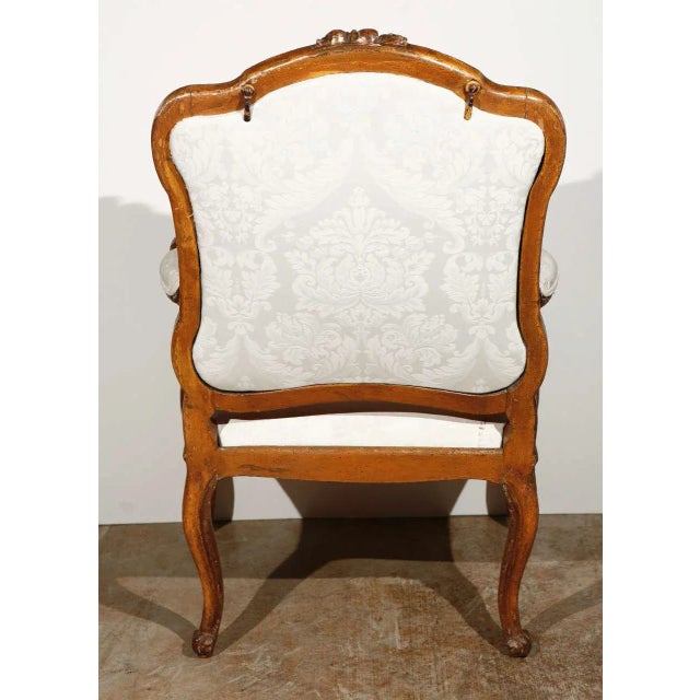 Hand-carved and gilded, Italian, open-arm, Rococo-style armchair with cabriole legs and elegant, serpentine arms. Top rail...