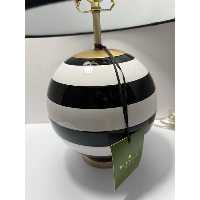 Brighten your space with chic, timeless style! This eye-catching Kate Spade table lamp features a bold black and white...