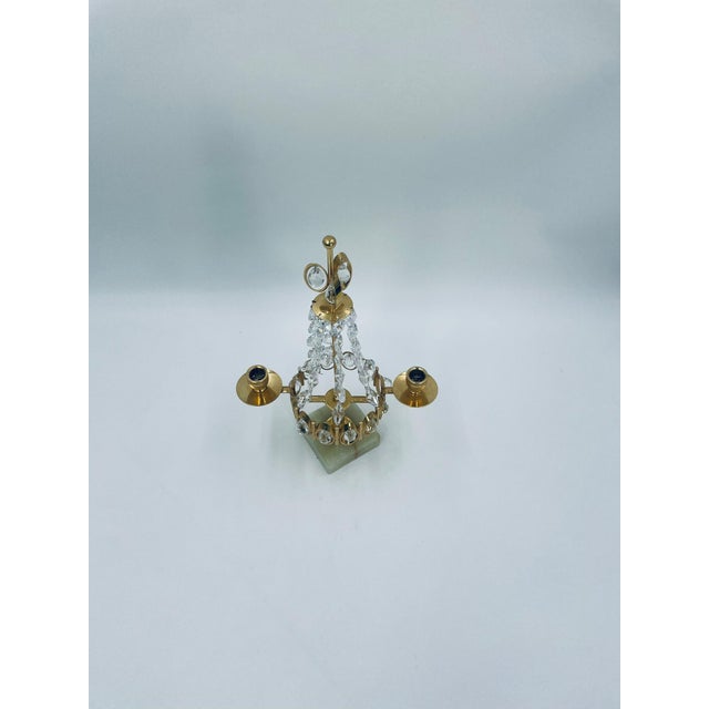 Decorative, two-armed candle holder in a vintage style. Crafted from brass and adorned with hanging crystals that...