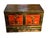 A Chinese hand painted elm chest in red with Asian motifs, carved detail and stencil work. The art on the front is...