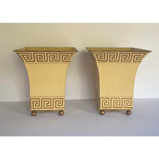 Fabulous vintage pair of hand painted metal cachepot vessels with gilt Greek key motif. These flared ball footed square...