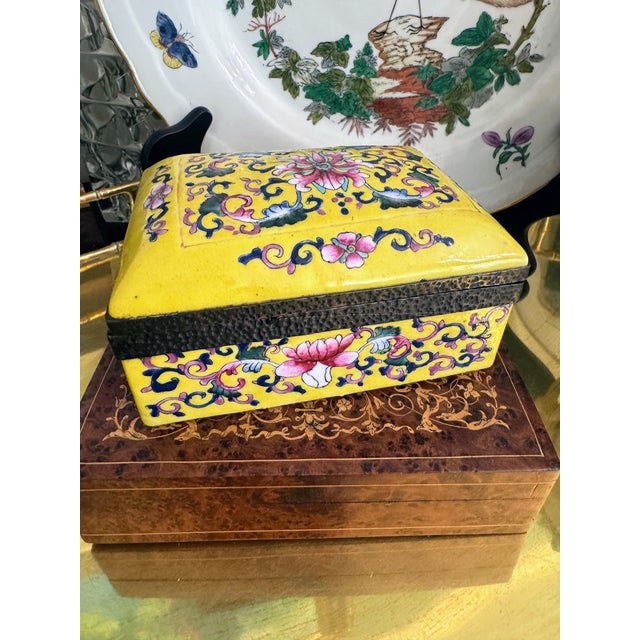 A striking chinoiserie porcelain lidded box finished in a richly saturated imperial yellow ground, adorned with finely...