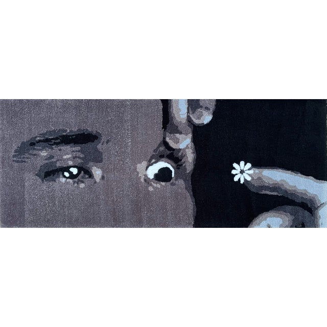 Up close, the work resolves into fragments: an eye, the bridge of a nose, the curve of a hand. Stepping back locks the...