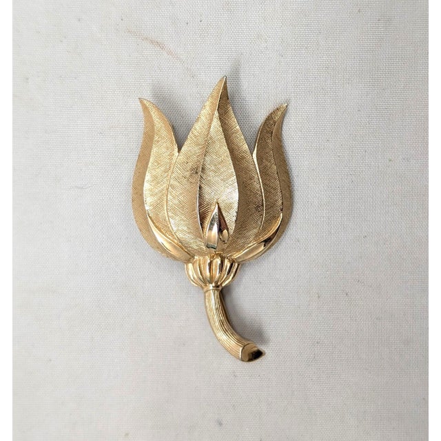 Circa 1960 goldtone textured tulip brooch with security clasp. Marked crown "TRIFARI" on the back. Measures: 1 1/8 inches...