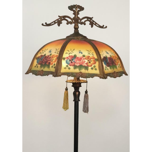 Art Nouveau style floor lamp with an ornate brass frame and a reversed painting textured glass shade. This requires two...