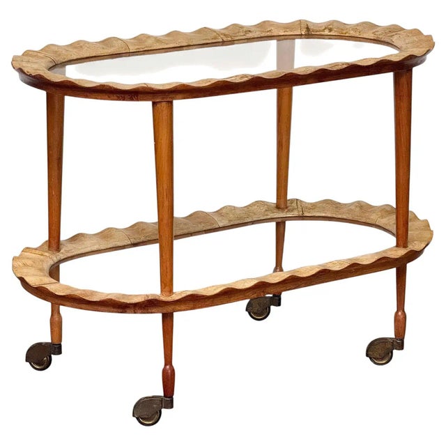 A fine two-tier Italian drinks cart or bar trolley of scalloped wood with tiers of glass from the Hollywood Regency...